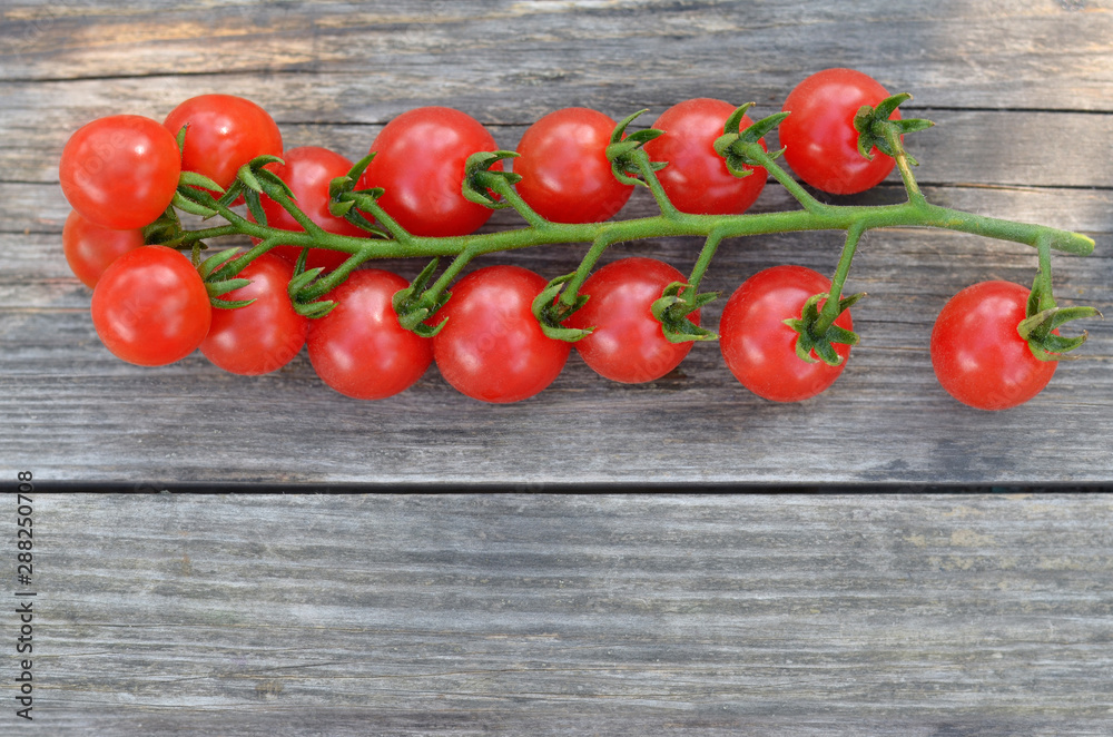 Red cherry tomatoes on a branch on a rustic background with copy space. Close-up, top view Red cherry tomatoes on a branch on a rustic background with copy space. Close-up, top view