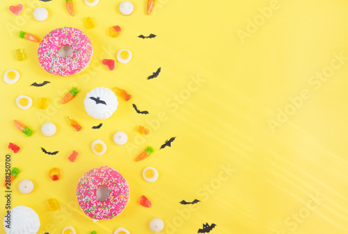 Halloween candy.Halloween holidays on yellow background, colorful decoration toys, baby sweets, donuts, marmalade. trick or treat, terrible night.Halloween background.copy space