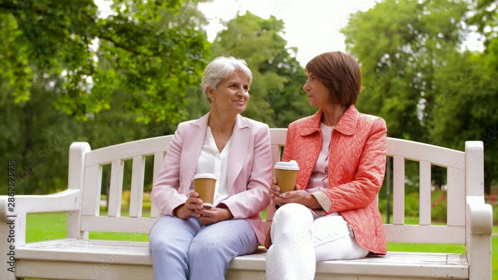 old age, retirement and people concept - two senior women or friends drinking coffee and talking at park old age, retirement and people concept - two senior women or friends drinking coffee and talking at park