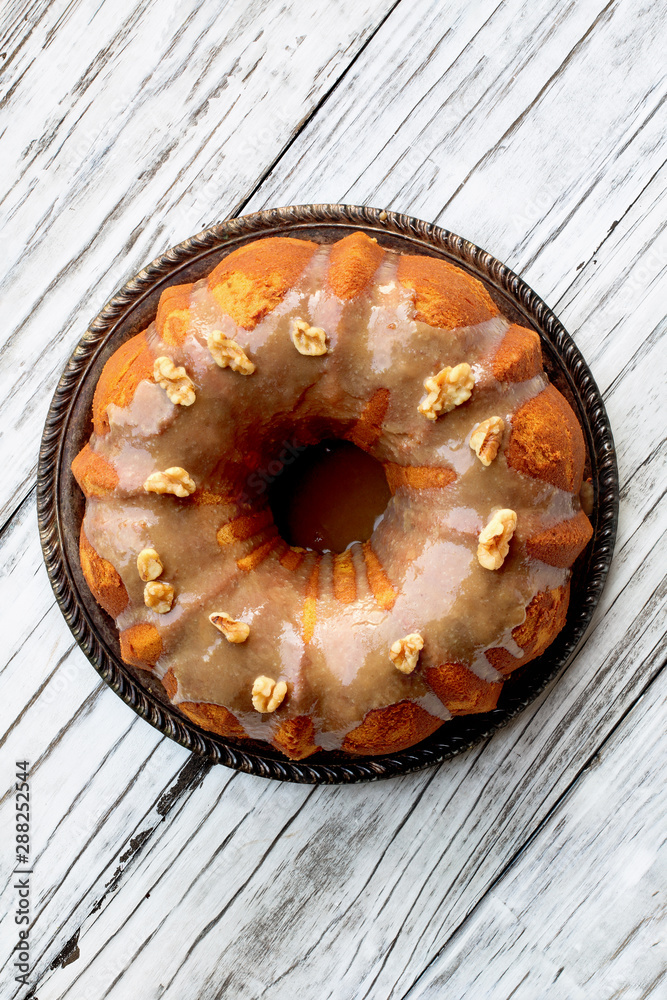 Φωτογραφία Delicious, Pumpkin Spice Bundt Cake frosted with brown sugar frosting and walnuts oven a rustic wood table background