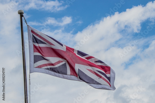 Union Jack flag flying in the wind on a cloudy blue sky day