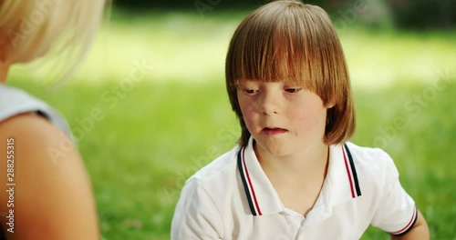 Preteen autistic boy in white polo shirt playing glose-ball with mother in park, mental development, Down syndrome