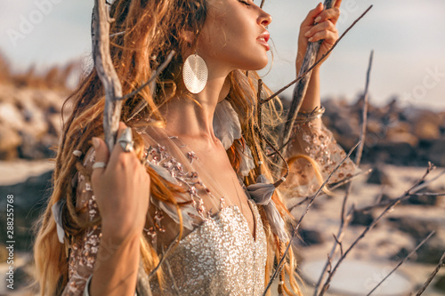 close up portrait of beautiful young woman model with boho accessories outdoors at sunset photo