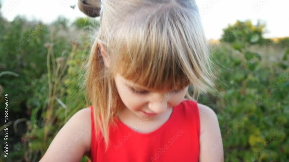 Girl eats ripe red juicy raspberry in the garden Girl eats ripe red juicy raspberry in the garden
