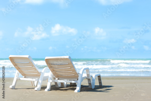 Summer Travel. White chair on sandy beach against blue sea and sky background  copy space. Summer vacation concept.