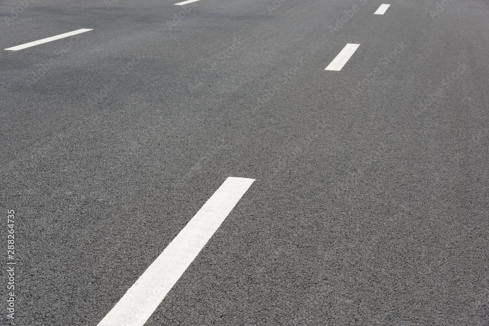 Low angle perspective view of two white paint dashed lines on asphalt road Low angle perspective view of two white paint dashed lines on asphalt road