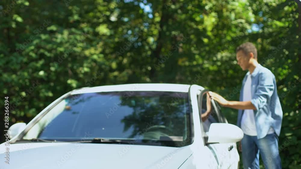 Black male getting out of car holding keys admiring new automobile, dealership Black male getting out of car holding keys admiring new automobile, dealership
