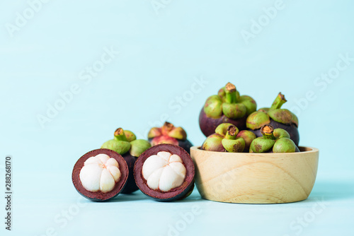 Mangosteen fruit in wooden bowl on pastel color background