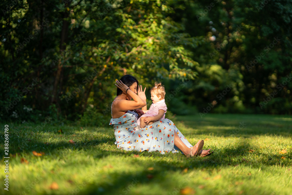 Mother sitting with baby on grass in park Mother sitting with baby on grass in park