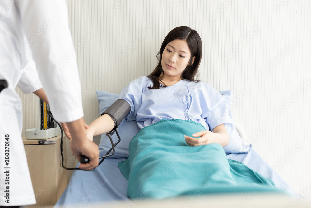 Obraz premium Doctor checking blood pressure of Asian women patient lying in a hospital bed