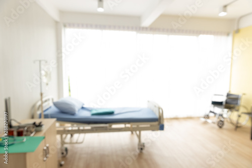 Blurred background of the patient room with a wheelchair, bed and the light from the window. © xreflex