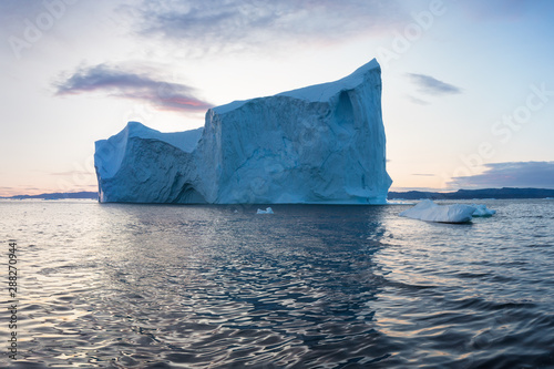 Icebergs in front of the fishing town Ilulissat in Greenland. Nature and landscapes of Greenland. Travel on the vessel among ices. Phenomenon of global warming. Ices of unusual forms and colors. 