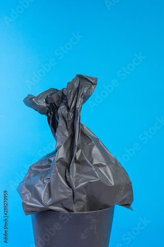 Black garbage bags that are on the black trash bin and have a blue background.