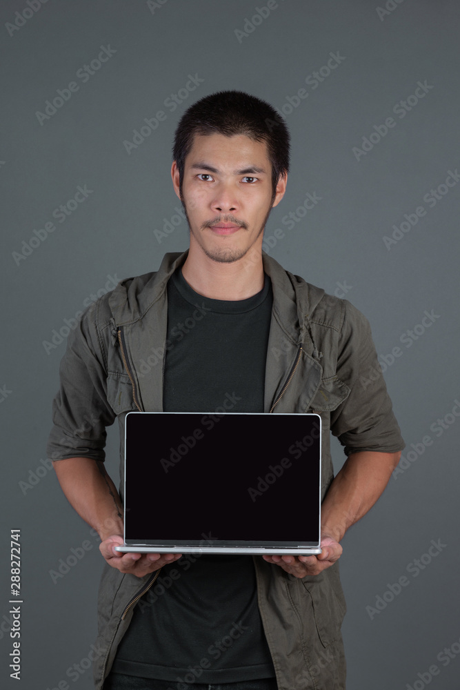 A handsome man with a notebook in his hand and a gray background.
