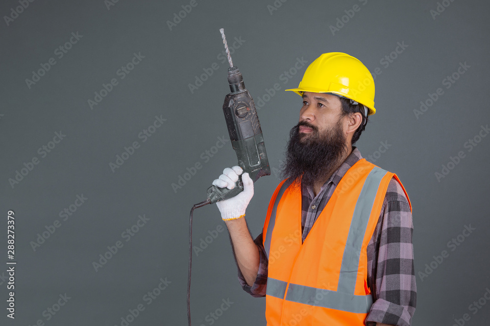 An engineering man wearing a yellow helmet with construction equipment on a gray background. An engineering man wearing a yellow helmet with construction equipment on a gray background.