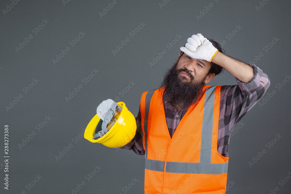 An engineering man wearing a yellow helmet wearing white gloves showed a gesture on a gray background. An engineering man wearing a yellow helmet wearing white gloves showed a gesture on a gray background.