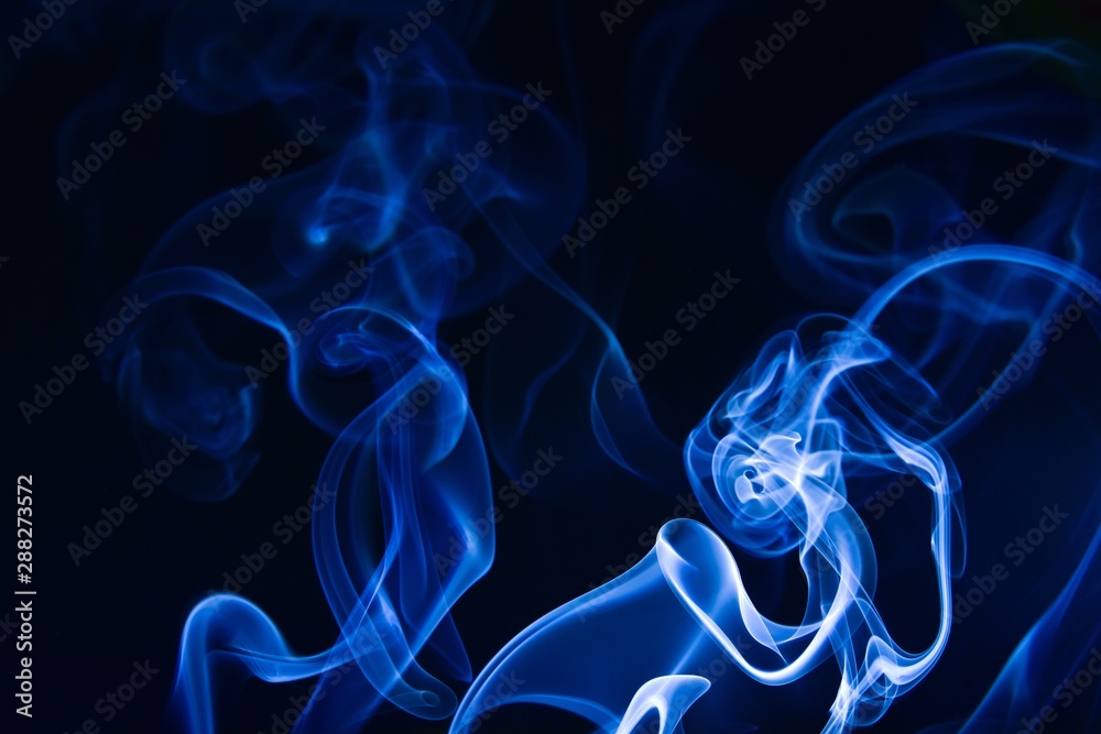 Fototapeta premium Incense smoke on a black background. Blue tone.