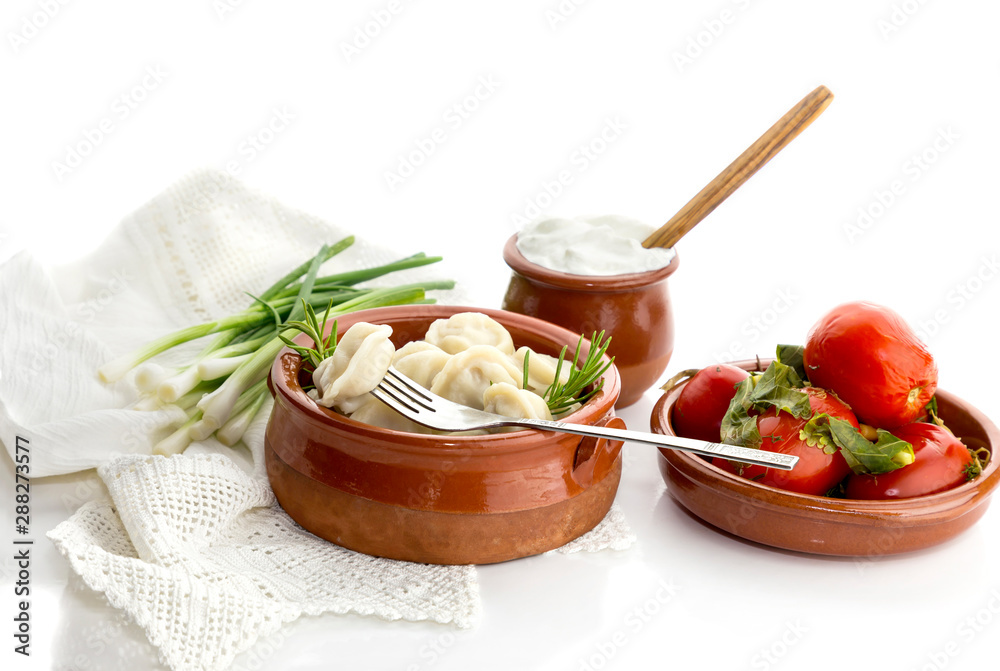Boiled dumplings in a bowl, sour cream and pickled tomatoes close-up (russian and ukrainian cuisine) Boiled dumplings in a bowl, sour cream and pickled tomatoes close-up (russian and ukrainian cuisine)