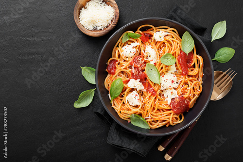 Spaghetti with tomato sauce, parmesan and mozzarella cheese decorated with basil.