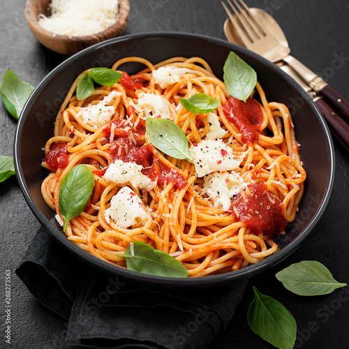 Spaghetti with tomato sauce, parmesan and mozzarella cheese decorated with basil.