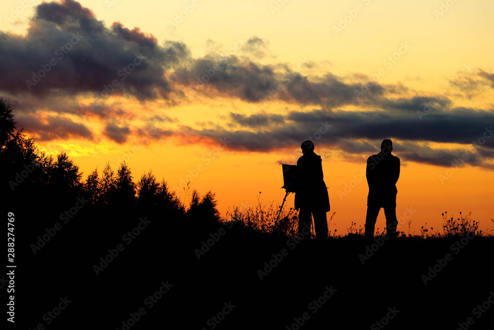 silhouettes of people couple of painters at the sunset