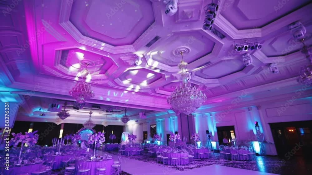 wonderful wedding hall with large lamps and decorated tables under purple electric light slow motion