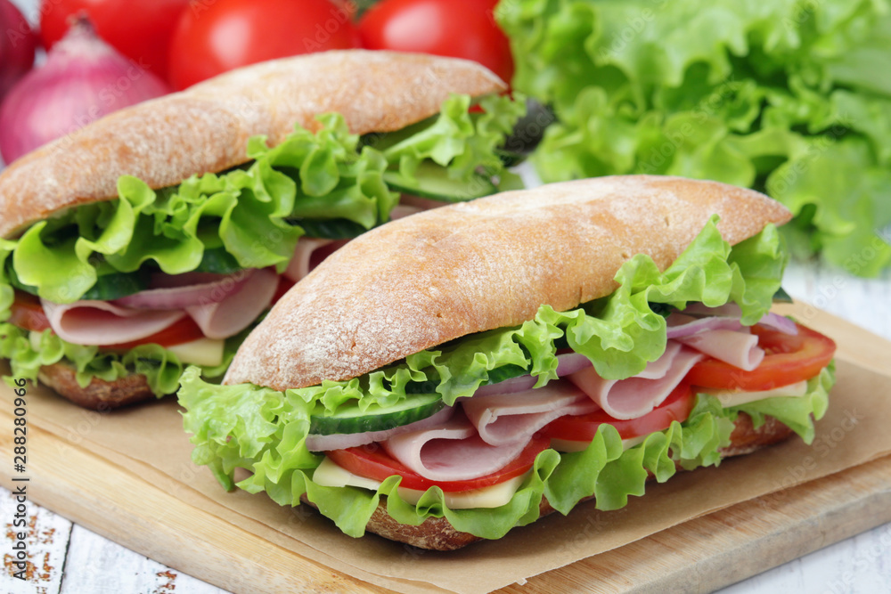 Two sandwiches with fresh vegetables, ham and cheese in ciabatta bread Two sandwiches with fresh vegetables, ham and cheese in ciabatta bread