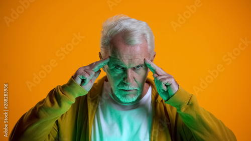 Elderly male mentalist demonstrating mind-reading power at camera, telepathy photo