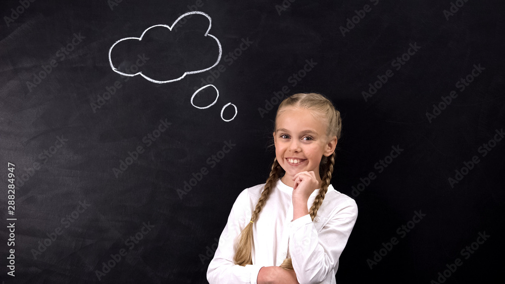 Smiling pupil looking at camera, idea sign on blackboard, creativity concept