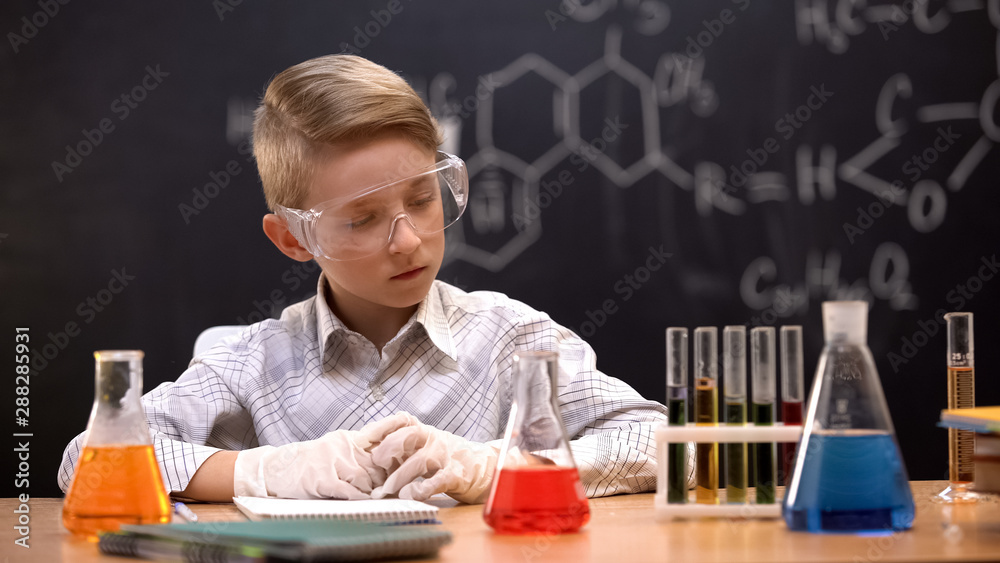 School experimenter looking at test tubes with liquids, analyzing reactions School experimenter looking at test tubes with liquids, analyzing reactions