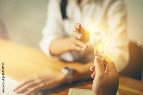 Sharing an idea concept, hand sharing a light bulb of idea to businesswoman photo