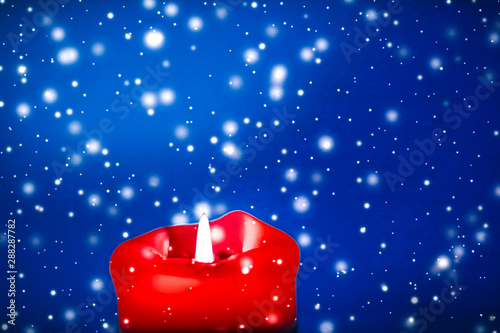 Canvas Print Red holiday candle on blue sparkling snowing background, luxury branding design