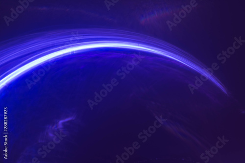 Blur neon blue arc lines, strokes. Bright falling comet light, glowing rays. Purple abstract art background. photo