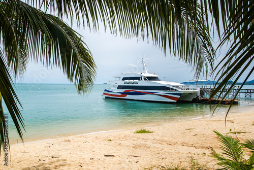 High-speed catamaran stands at the pier, located on a sandy beach . Koh Samui Thailand.