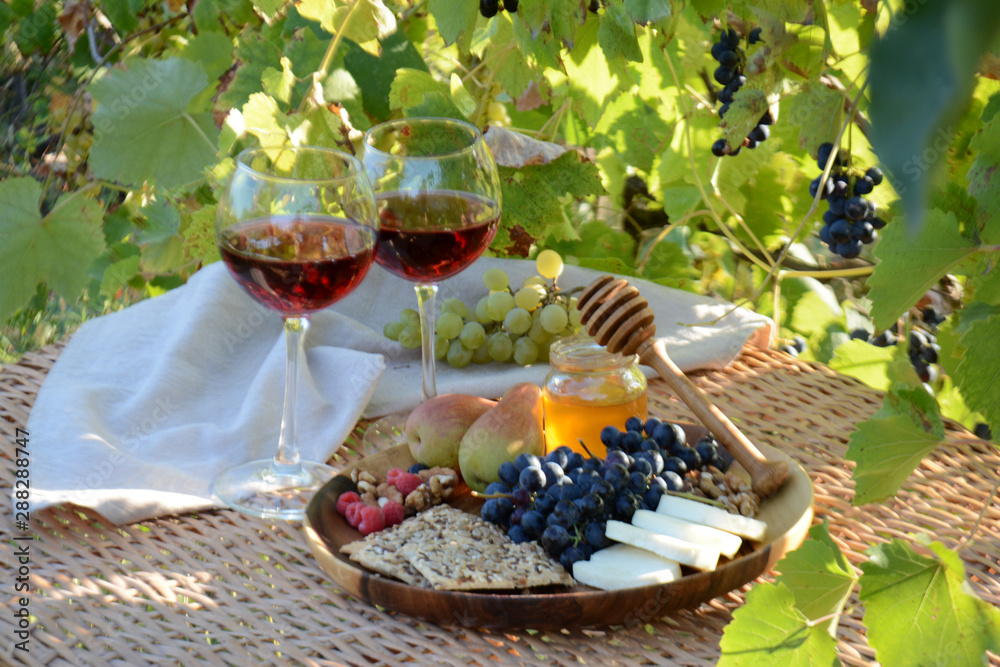 Autumn picnic in the garden Wine glasses and wine snacks on a wicker table outdoor Lunch in nature