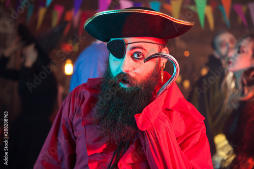 Obraz na plátně Portrait of funny man in a pirate costume playing with his hand hook at hallowee