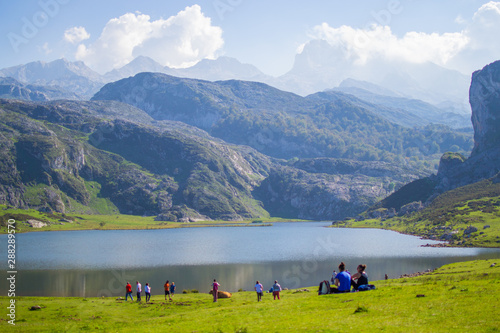 Beautiful view of Ercina Lake in Covadonga Lakes, Asturias, Spain. Green grassland with people relaxing and mountains at the background