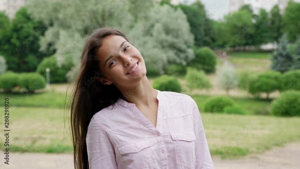 happy stylish girl with long loose hair smiles and poses against white blooming tree in green park close view happy stylish girl with long loose hair smiles and poses against white blooming tree in green park close view