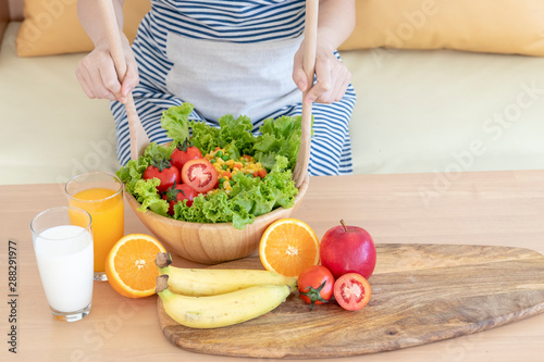 woman preparing salad or healthy meal in kitchen.