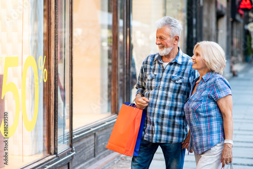Happy senior couple in shopping looking at window