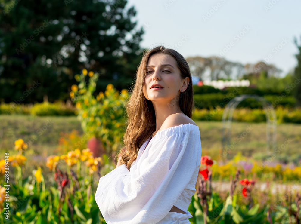 Young beautiful woman with bare shoulders in white clothes in the park in summer Young beautiful woman with bare shoulders in white clothes in the park in summer