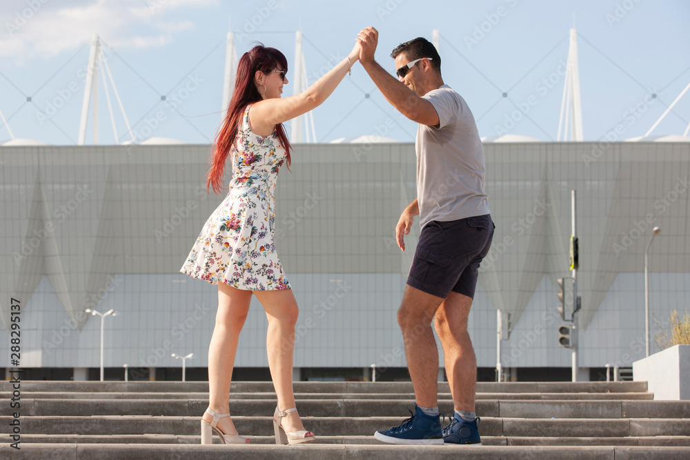 Young couple dancing Latino dance against urban landscape.