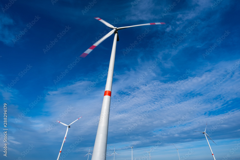 Windkraftanlage mit Langzeitbelichtung, leicht bewölkter blauer Himmel im Hintergrund