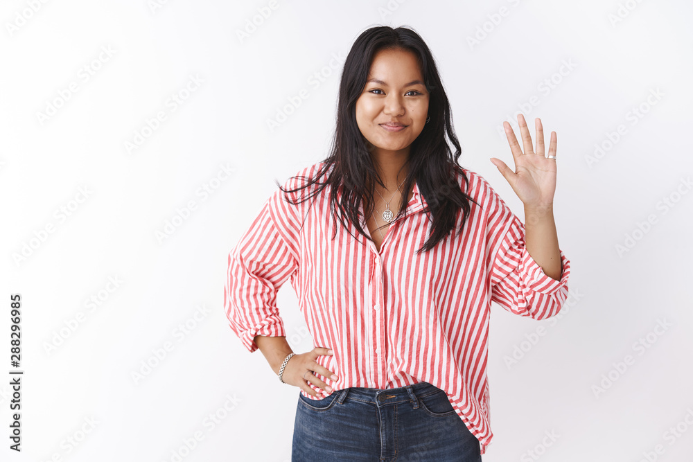 Studio shot of friendly and outgoing attractive new female coworker meeting coallegues waving hand in hello or hi gesture holding arm on hip greeting getting know people over white background Studio shot of friendly and outgoing attractive new female coworker meeting coallegues waving hand in hello or hi gesture holding arm on hip greeting getting know people over white background