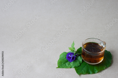 A cup of tea on leaf with brown paper background.
