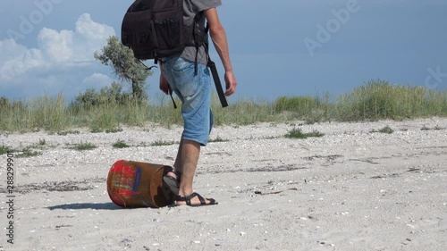 A man walks past a rusty iron can on the Black Sea coastline photo