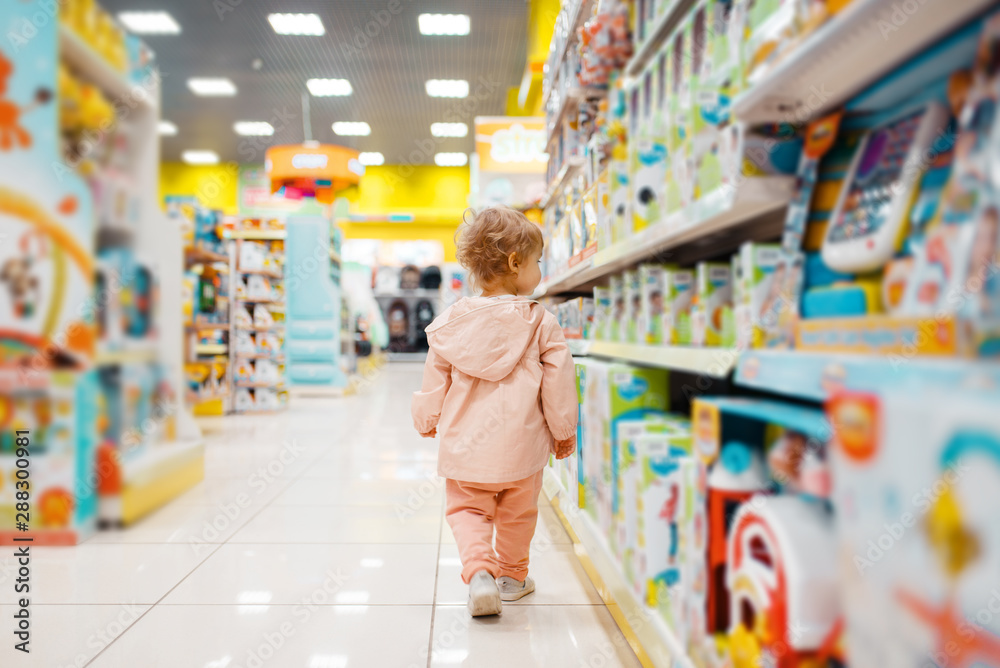 Little girl choosing toys in kids store - obrazy, fototapety, plakaty 