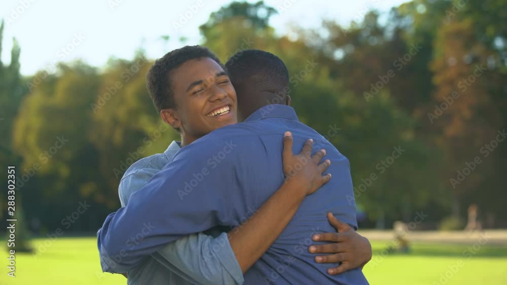 Male teenager hugging elder brother outdoors, family meeting happiness, love Male teenager hugging elder brother outdoors, family meeting happiness, love