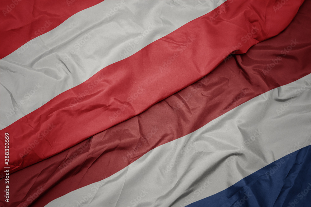 waving colorful flag of netherlands and national flag of austria.