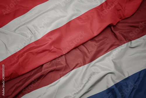 waving colorful flag of netherlands and national flag of austria.